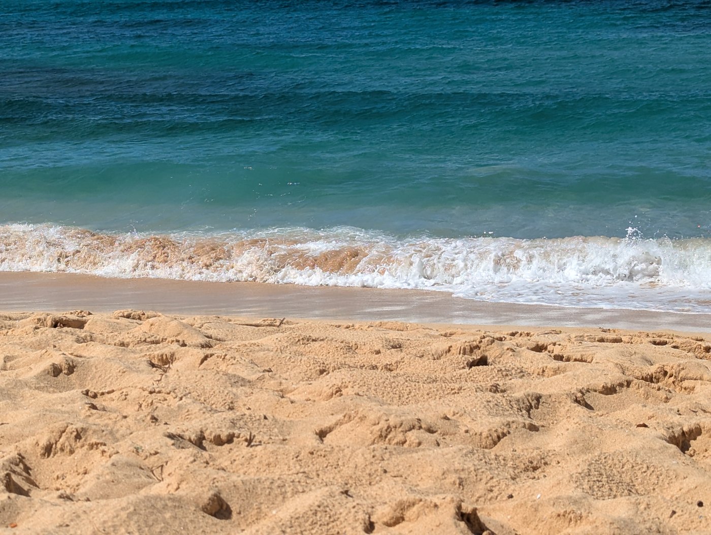 Gentle waves meeting a sandy shoreline